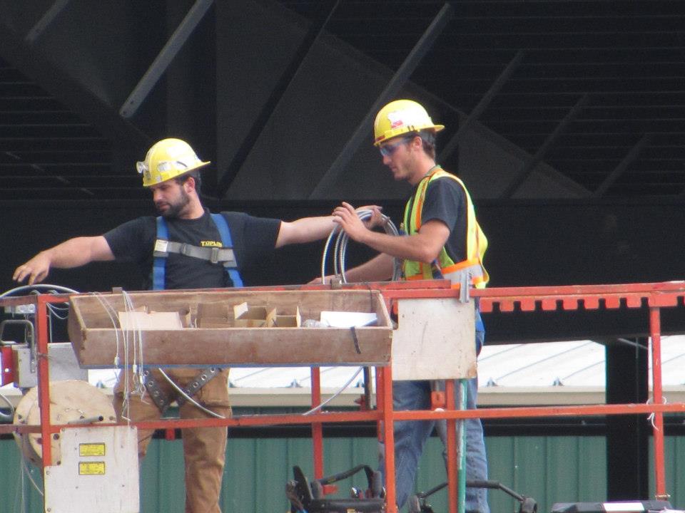 Topline Electric workers on a lift at a job site